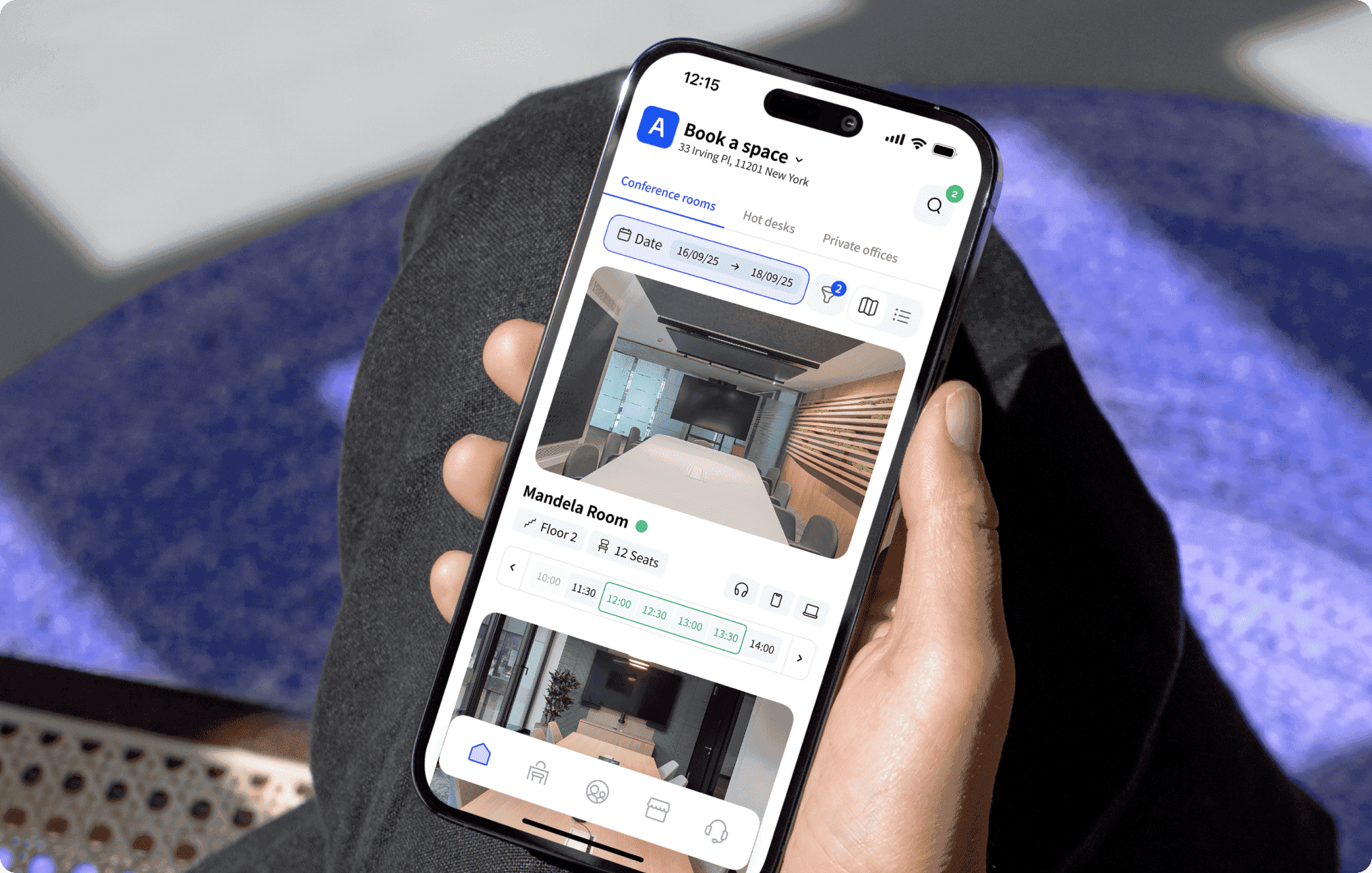 A person holding a smartphone displaying Archie Mobile app. The app shows available conference rooms, and allows users to select booking times.