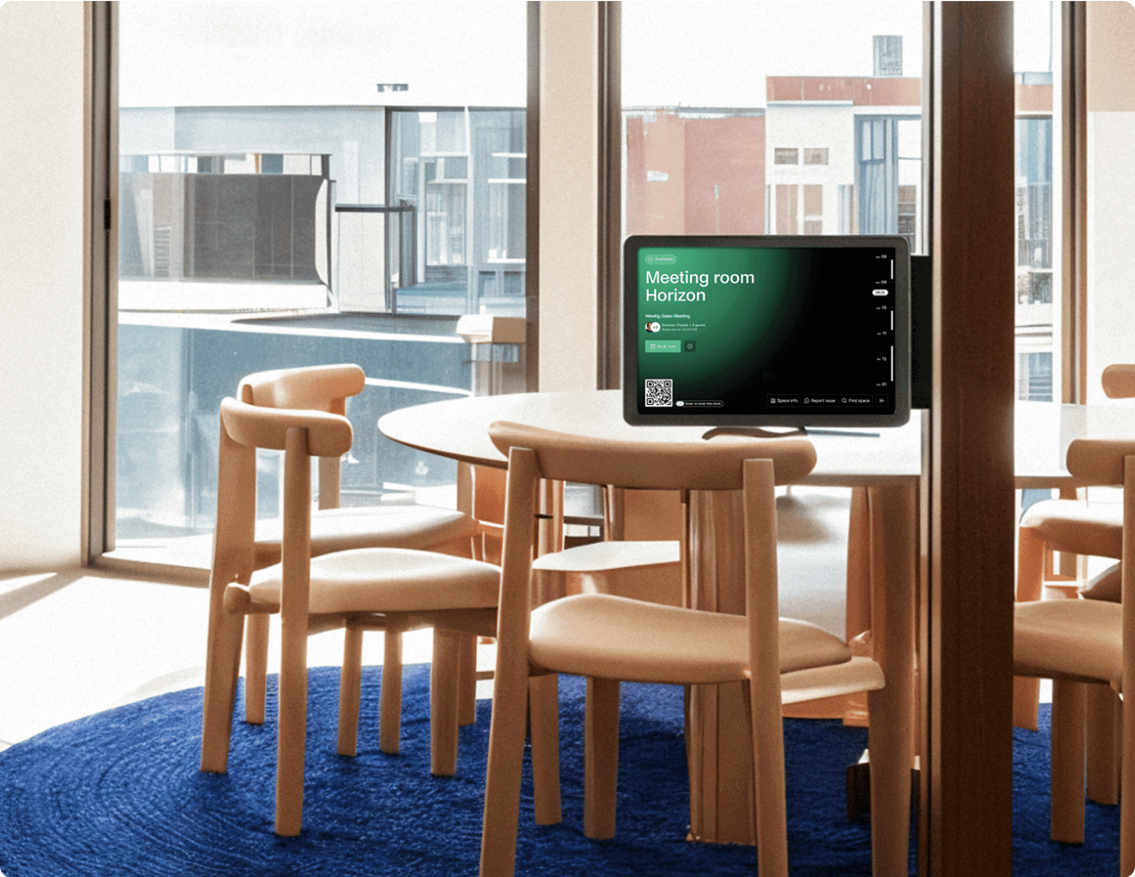 A tablet mounted outside a meeting room named "Horizon," displaying booking details and a QR code for check-in, with a view of a modern meeting space with wooden chairs and a round table.