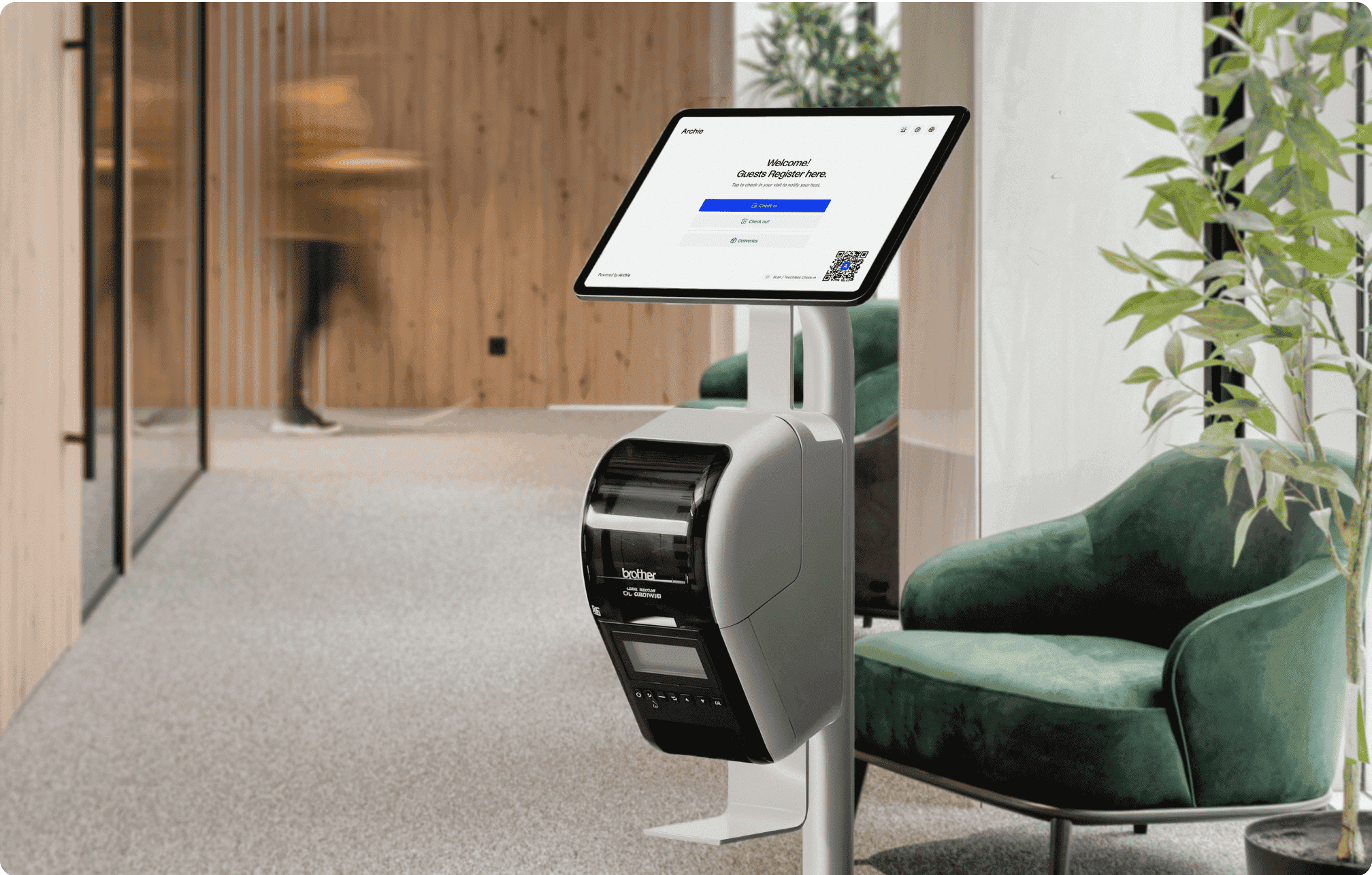 Tablet on a stand with a guest registration screen from Archie Visitors app and a label printer attached.