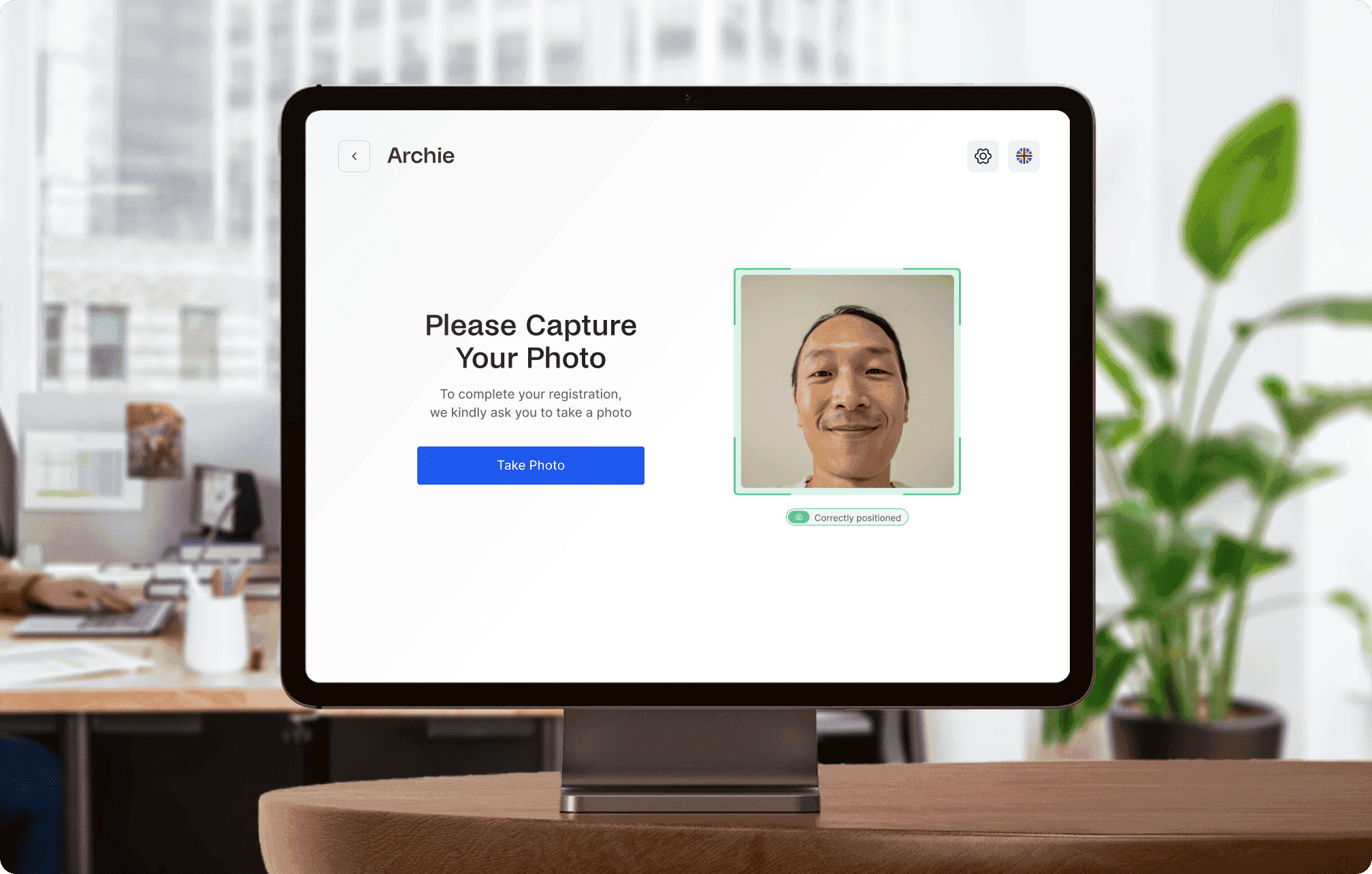 Tablet screen with Archie Visitors app prompting the user to capture their photo for registration.