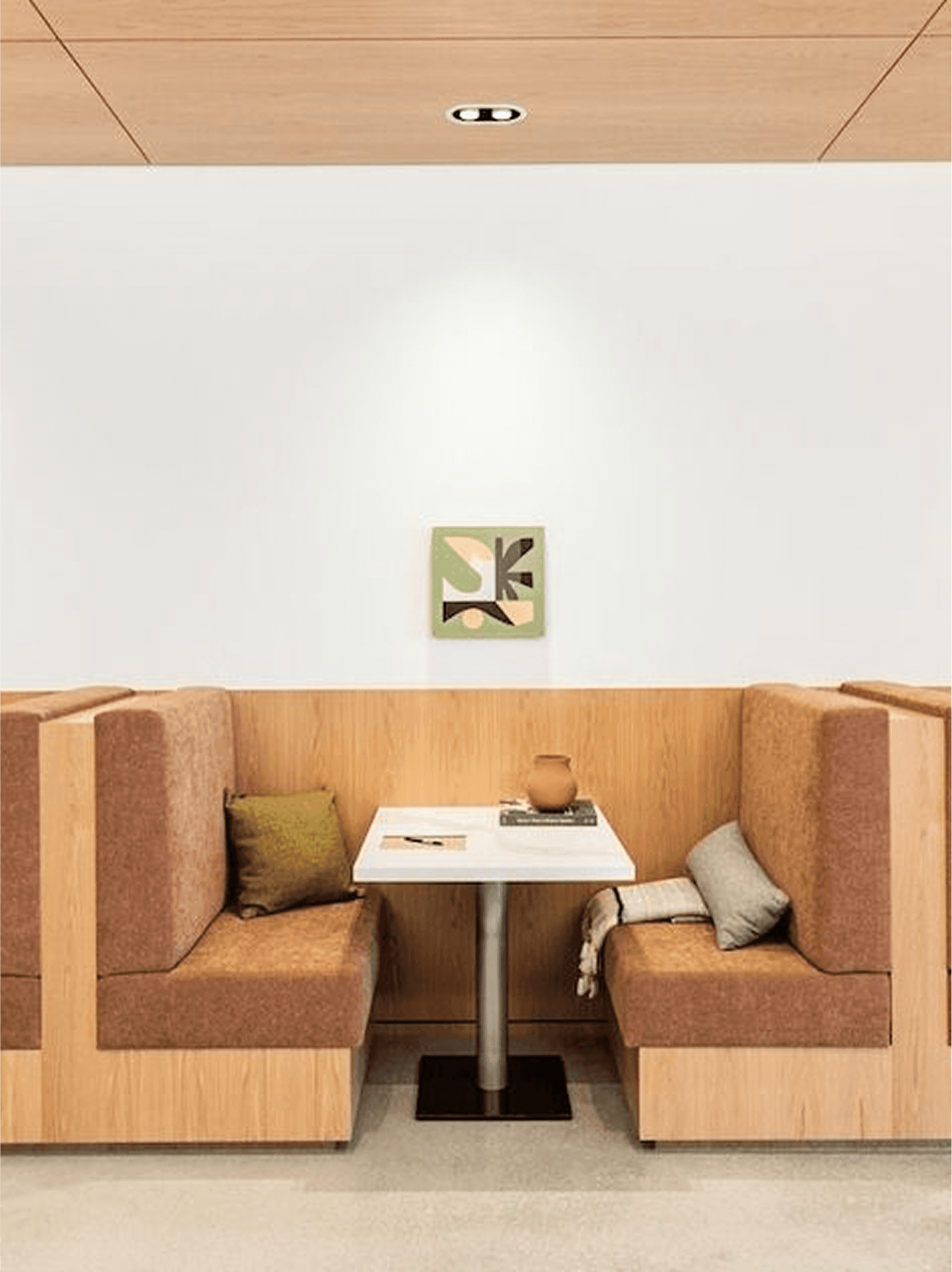 A cozy booth with wooden paneling, cushioned seats, and a small table with decorative items