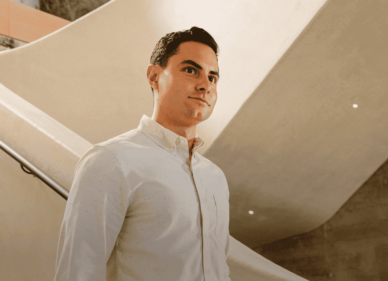 A man in a white shirt standing near a staircase